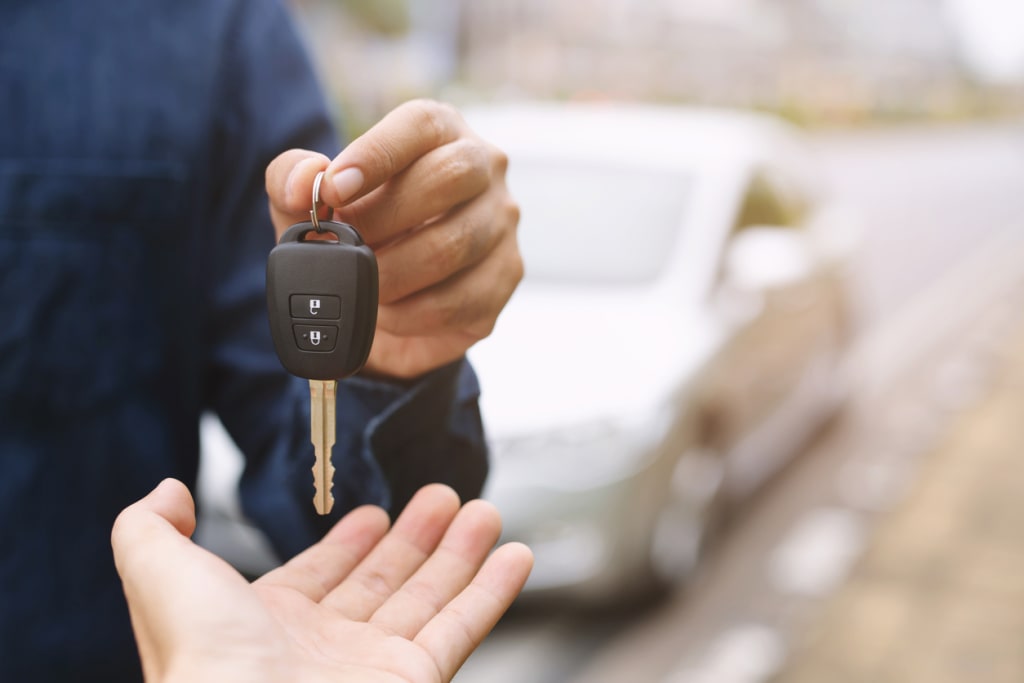 A close-up image of a person handing over a car key to a friend